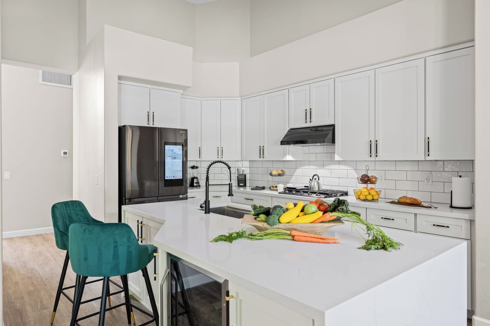 Modern kitchen featuring white cabinetry and a large island with a wine fridge.