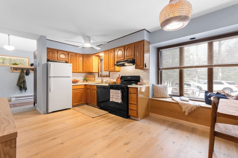 Bright, fully equipped kitchen with warm wood cabinetry, modern appliances, and a sunny window—perfect for easy meals and cozy mornings in.