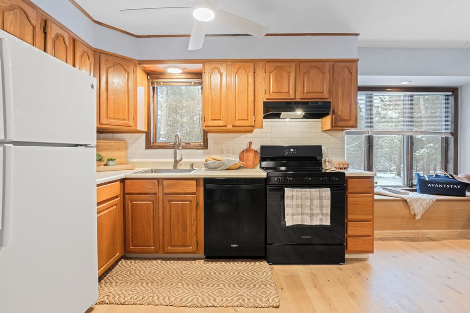 Bright, fully equipped kitchen with warm wood cabinetry, modern appliances, and a sunny window—perfect for easy meals and cozy mornings in.