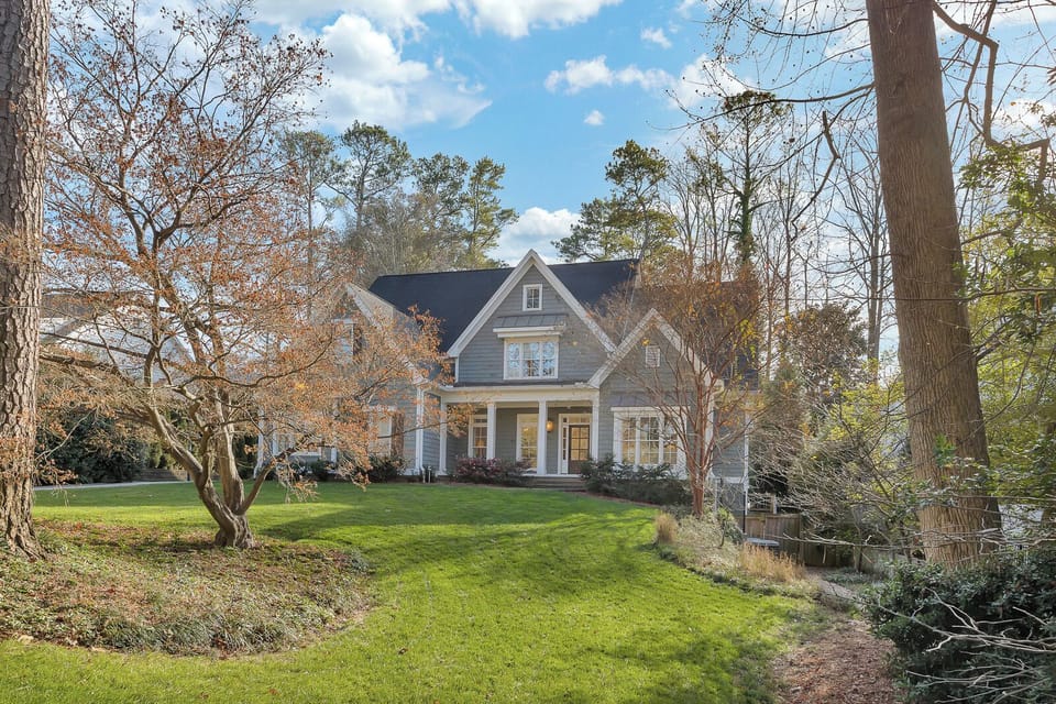 Wide front yard framed by trees, offering a peaceful welcome home
