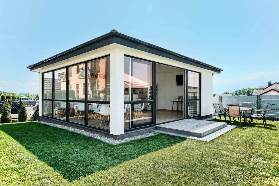 A small, modern building with large windows, flat rooflines, and a lawn surrounding the structure.