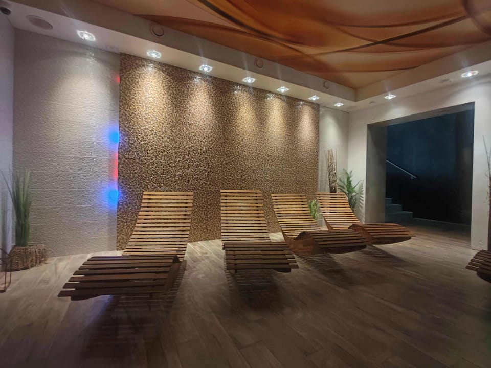 A dimly lit relaxation room with loungers, textured walls, and ambient spa lighting.