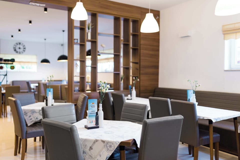 A modern restaurant interior with tables, upholstered chairs, and wooden divider elements.
