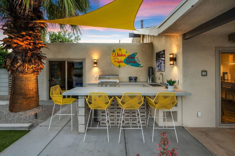 Outdoor bar at sunset with grill, seating & ambient lighting