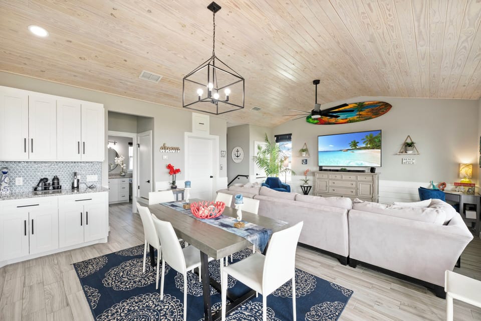 Relax in your stylish open-plan living space where coastal charm meets modern comfort, complete with a fully-equipped kitchen and cozy seating.