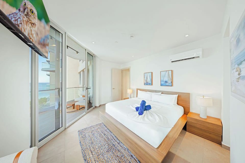 Sink into crisp white linens and wake to serene ocean glimpses from your private balcony. This bright, airy bedroom is your peaceful retreat after sunny days exploring.