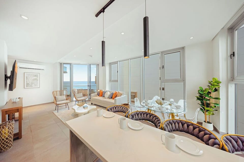 Your open-concept haven blends living and dining areas where natural light pours through expansive windows, framing stunning ocean views—perfect for morning coffee or sunset cocktails.