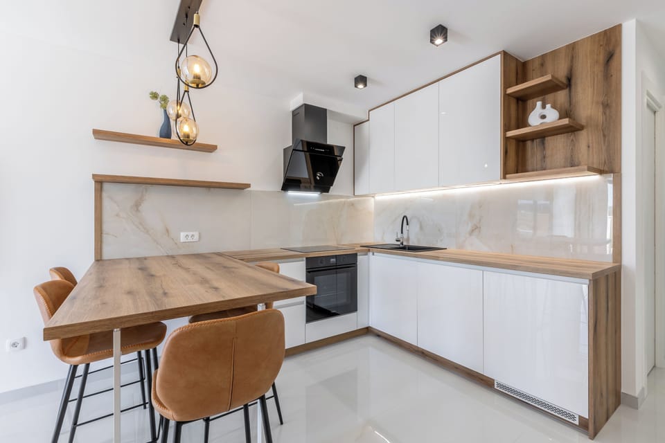 Modern elegant kitchen with soft tones and a connected dining area.
