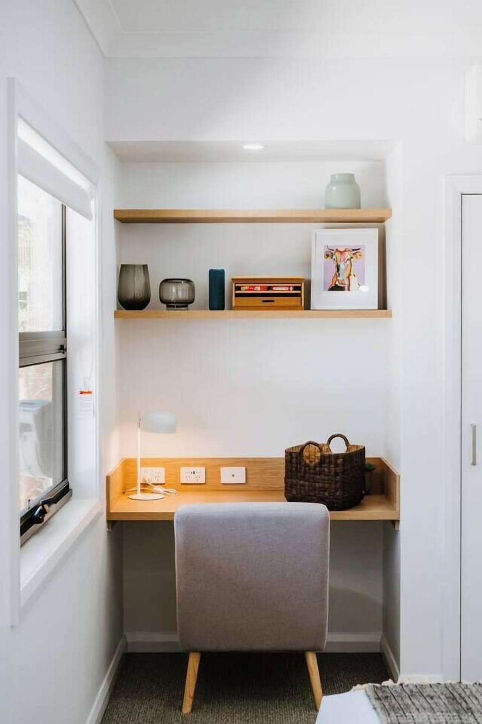 A built-in workspace with timber shelving and natural light supports remote work or quiet planning moments.