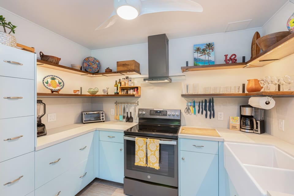 Open shelving, coastal touches, and an electric range make this kitchen both stylish and functional.