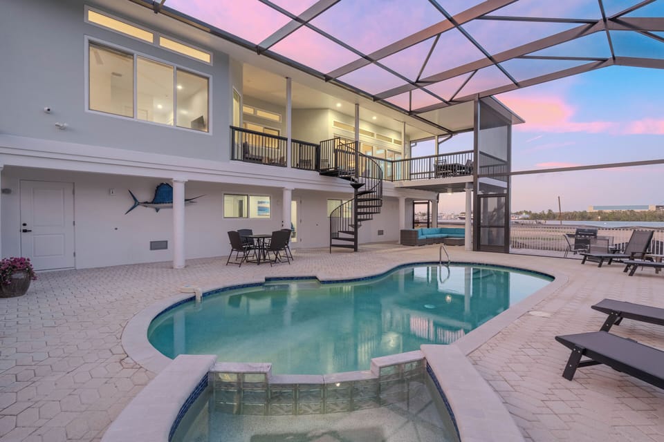 Stunning waterfront villa with screened pool area perfect for sunset swims and outdoor dining under the twilight sky.