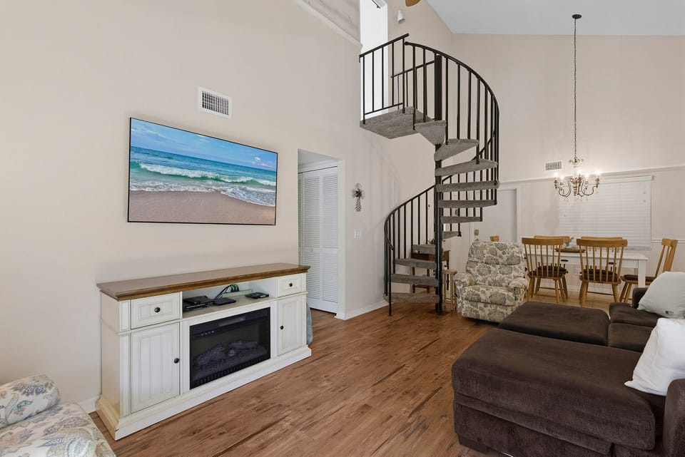 Charming beach stay featuring a stylish spiral staircase, open-concept living and dining area, and cozy fireplace. This inviting vacation rental blends coastal décor and comfort for a relaxing seaside getaway.