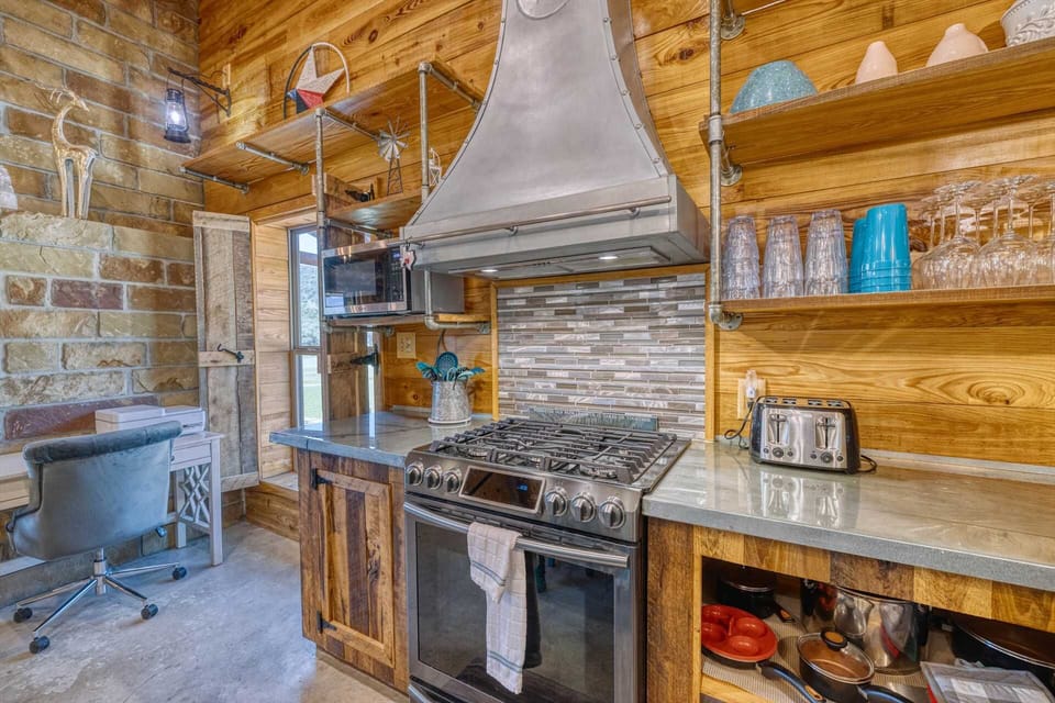 A chef-ready kitchen featuring a gas range, open shelving, and handcrafted details throughout