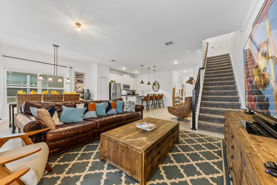 Open-concept comfort: a roomy leather sectional, colorful pillows, and a farmhouse coffee table flow into the modern kitchen with pendant-lit island seating-perfect for movie nights and meals together.