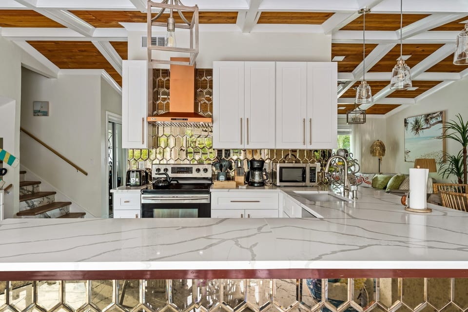 Impeccably designed Kitchen with stainless appliances, mirrored back splash, marble countertops and designer lighting