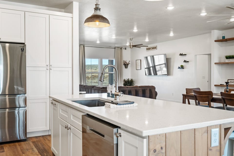 Modern kitchen featuring quartz countertops, island with sink, and stainless steel appliances.