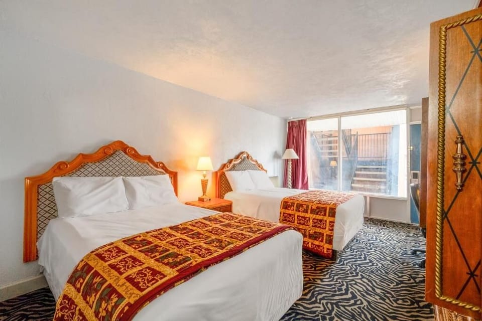 Unwind in a bright double-queen room with cozy bedding.