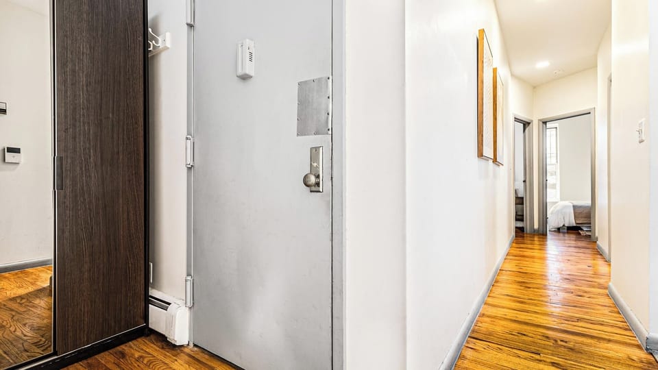 Step into your private entrance hallway, where gleaming hardwood floors guide you toward bright, welcoming bedrooms and modern living spaces.