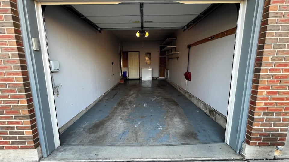Single-car garage with chest deep freezer and baby gear.