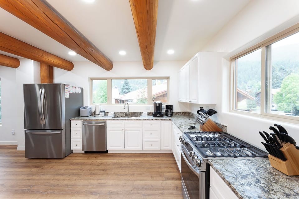 Your gourmet kitchen features granite counters, stainless appliances, and warm wood beam ceilings—perfect for creating memorable meals with stunning mountain views just beyond the windows.