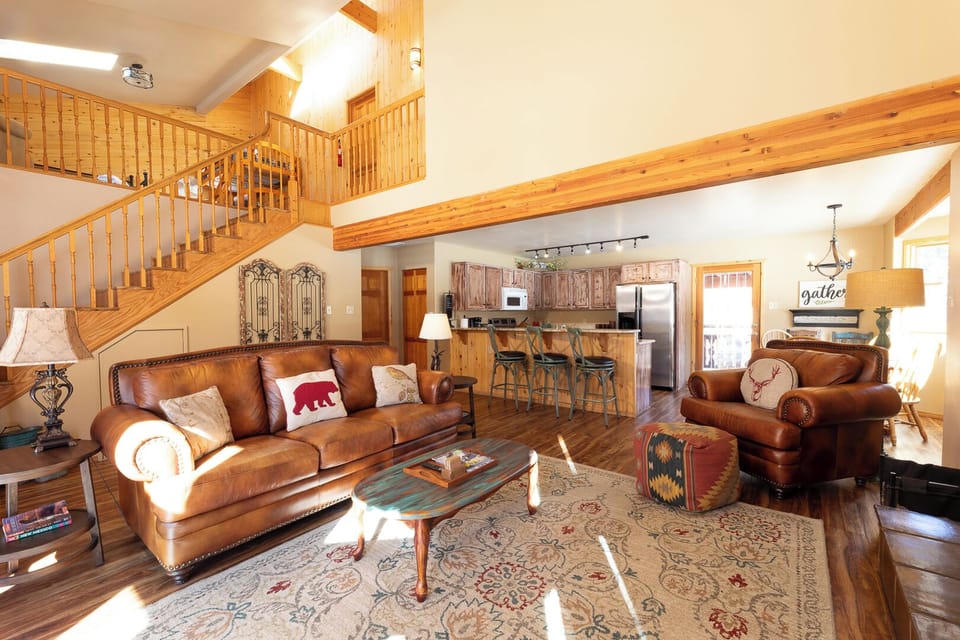Sink into plush leather sofas beneath soaring wood beams and sunlit windows. The open-concept living area flows into a fully equipped kitchen, perfect for gathering after mountain adventures.