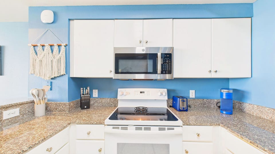 Relax in this bright coastal kitchen where ocean blues meet modern convenience, complete with granite counters and stainless appliances for your comfort.