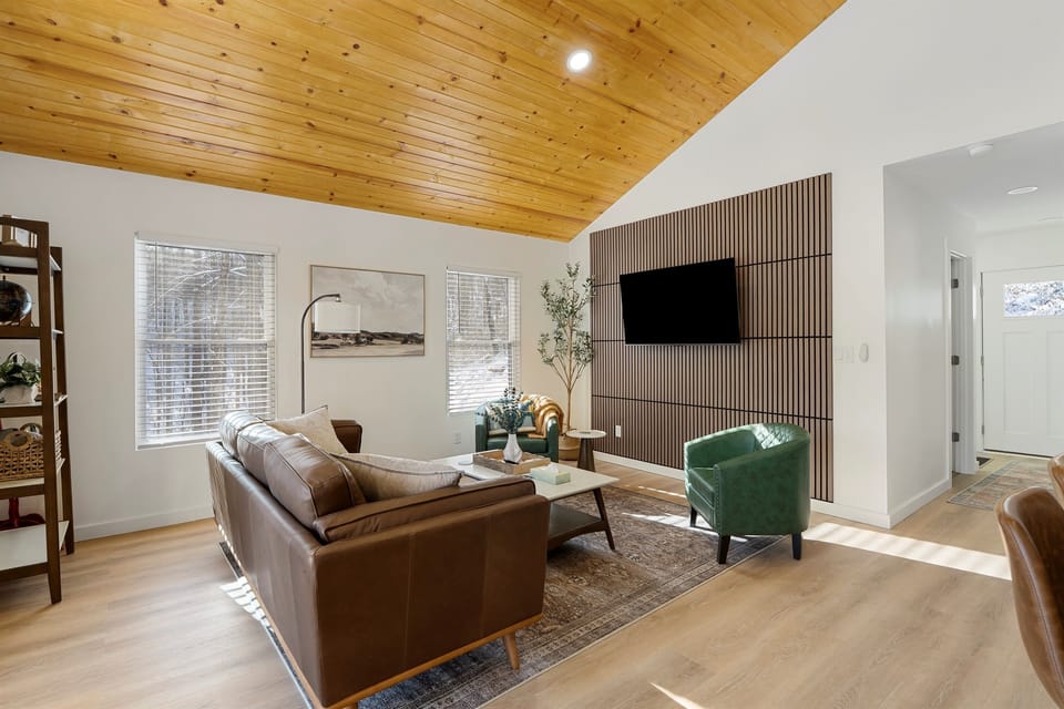 Bask in natural light and pond views from this stylish open-concept living area—featuring a fully equipped kitchen, cozy seating, and direct access to the outdoor deck.