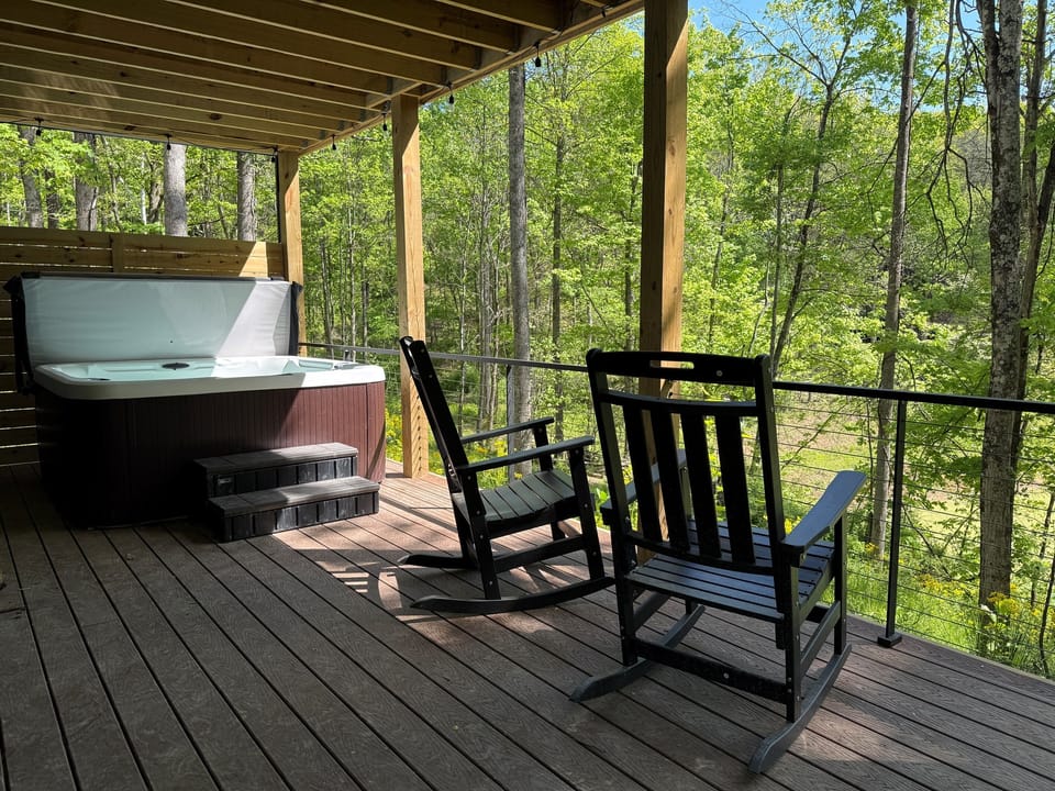 Covered lower deck with hot tub at Sherwood — personal hot tub tucked under the covered deck, seating area alongside, wooded views