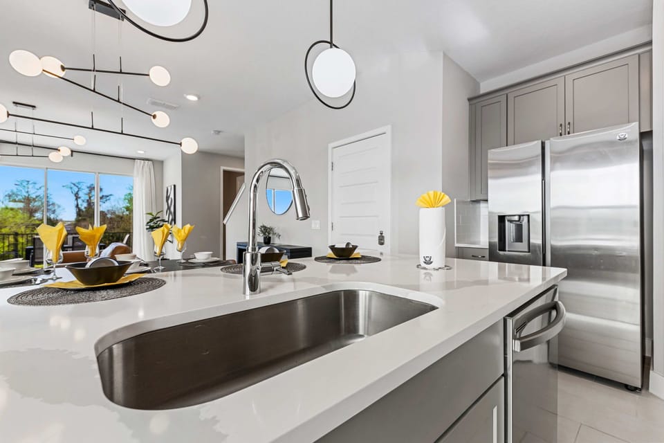 Bright chef's kitchen with a roomy island, deep sink, and stainless fridge-serve meals at the breakfast bar while enjoying the open‑concept vibe.
