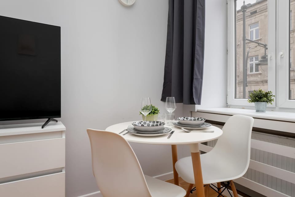 The dining table by the window offers a pleasant spot for meals with natural light and a city view, perfect for calm mornings and relaxed evenings.