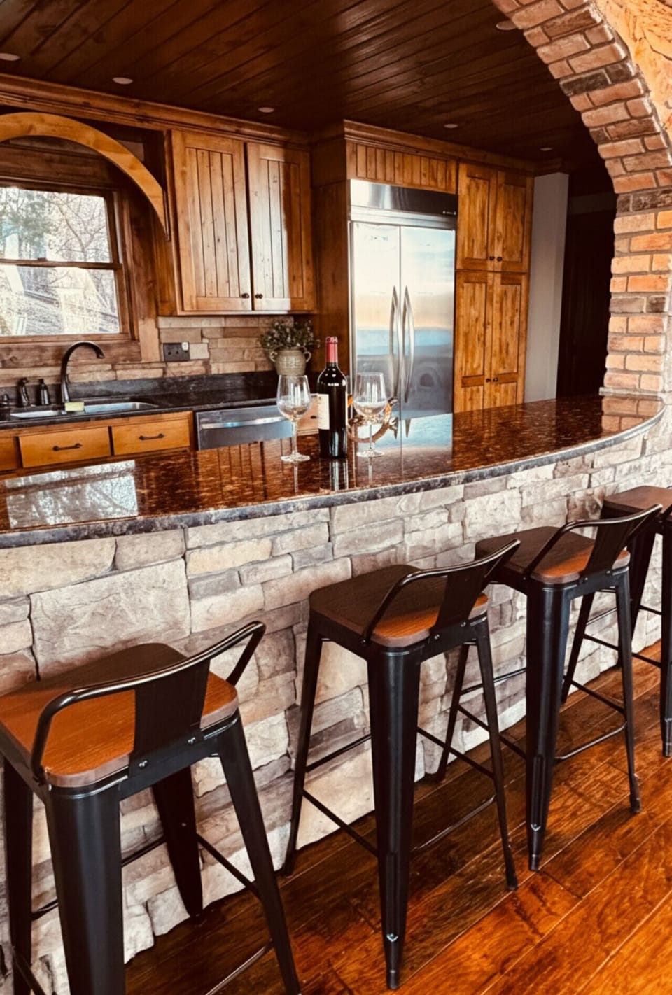 Rustic luxury kitchen with stone bar, granite countertops, and stylish seating, perfect for entertaining and enjoying upscale lake house vacations. 🍷🏡