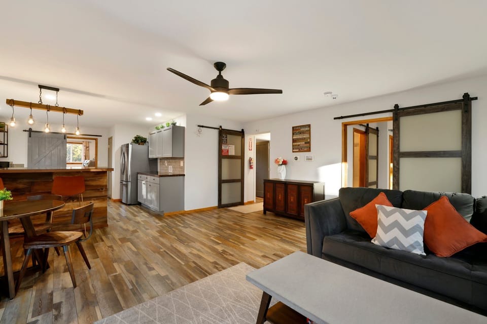 Cozy mountain living room with a stone fireplace, comfy seating, and smart TV—perfect for relaxing evenings, movie nights, and warm cabin vibes after outdoor adventures.
