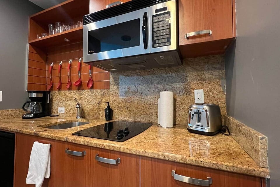 Cozinha compacta e completa com todos utensílios necessários, microondas/forno, cooktop, mini-refrigerador, tostadeira e máquina de café em pó.