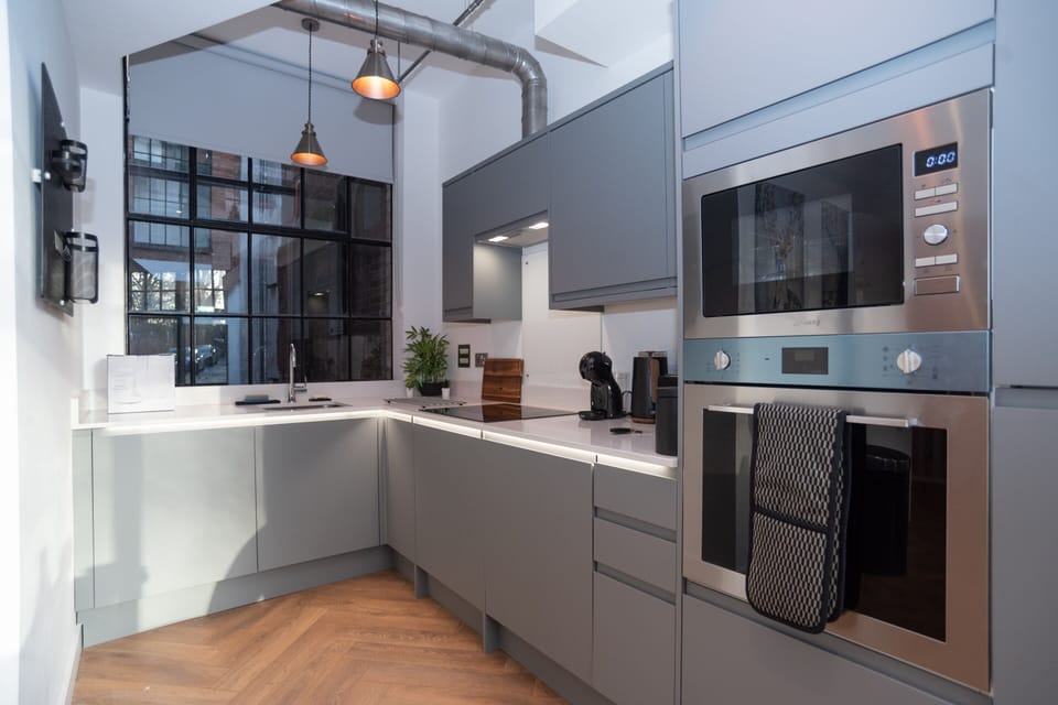 Bright modern kitchen with integrated appliances including dishwasher, oven, microwave and washing machine, plus complimentary tea and coffee.