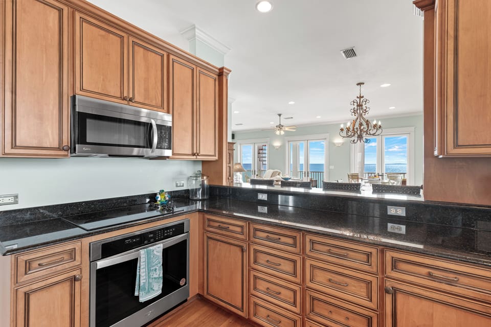 Your gourmet kitchen features rich wood cabinetry, granite counters, and stainless appliances—perfect for creating memorable meals with stunning views beyond.