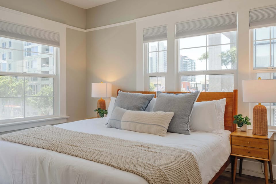 Wake up to sunshine and city views in this serene, light-filled bedroom.