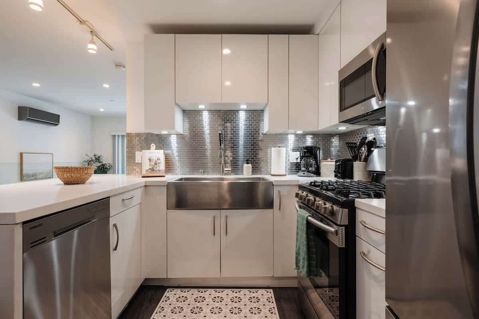 The kitchen features a modern stainless steel splashback and deep double sink