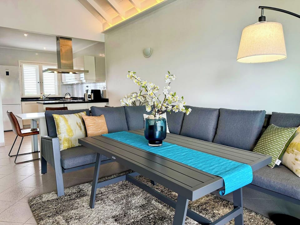 The living room features a large L-shaped sofa and an open, spacious layout.