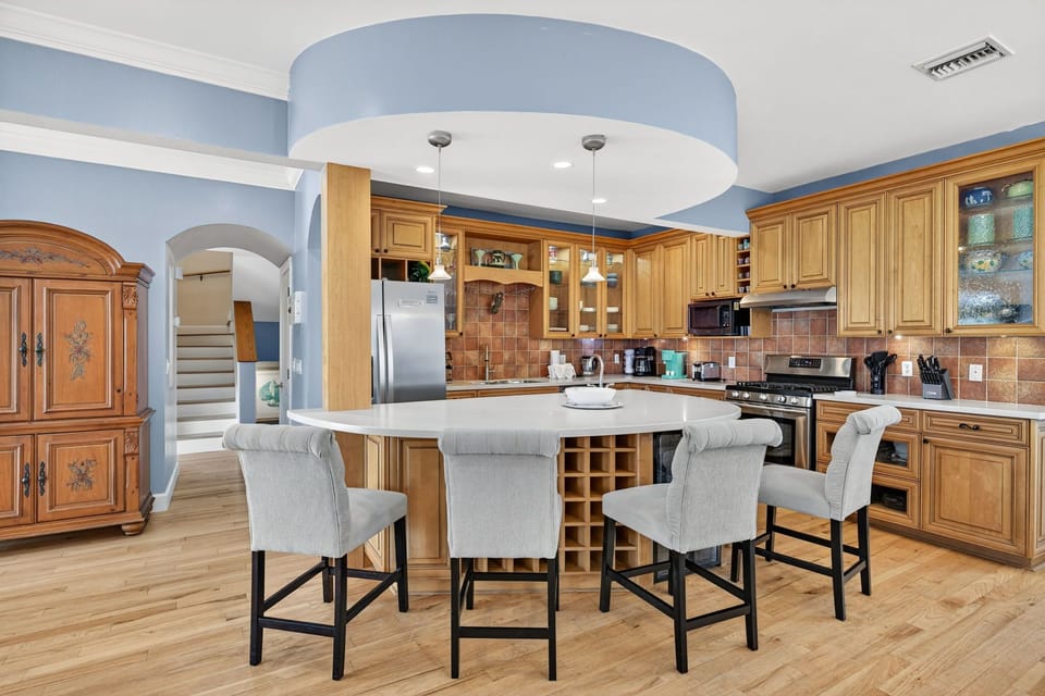 Spacious, high-end kitchen featuring custom wood cabinetry, a large center island, and warm coastal design accents.
