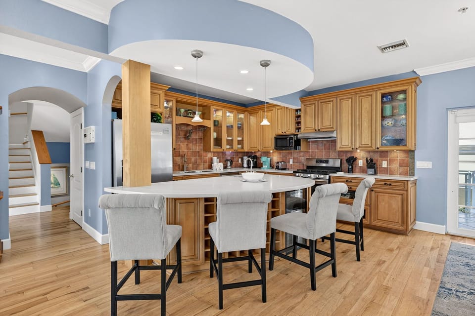 Spacious, high-end kitchen featuring custom wood cabinetry, a large center island, and warm coastal design accents.