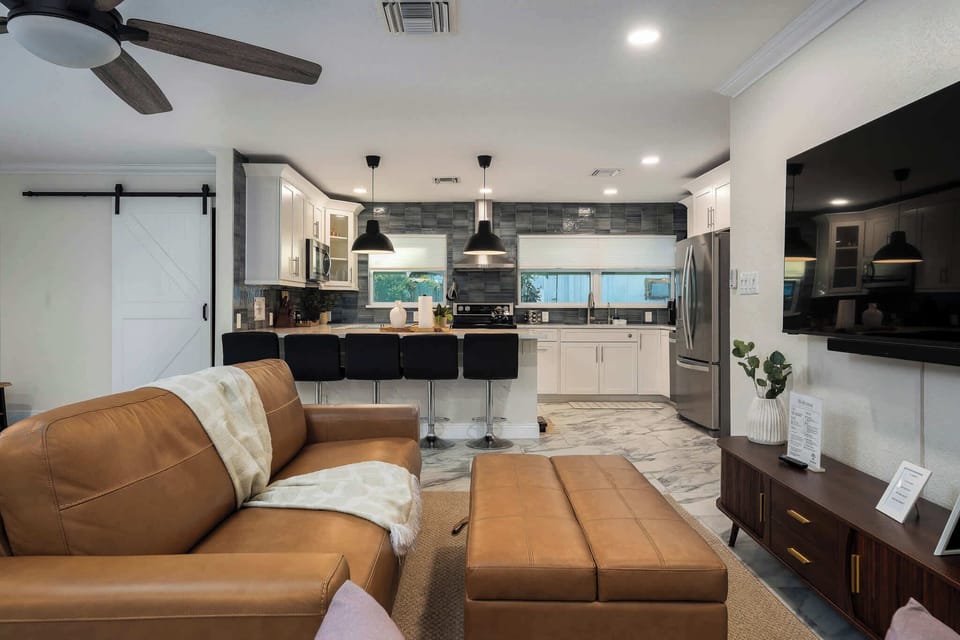 Relax in this open-concept living space featuring cozy leather seating, modern décor, and a sleek kitchen with bar seating. Perfect for gathering, movie nights, or unwinding after a day of fun and adventure.