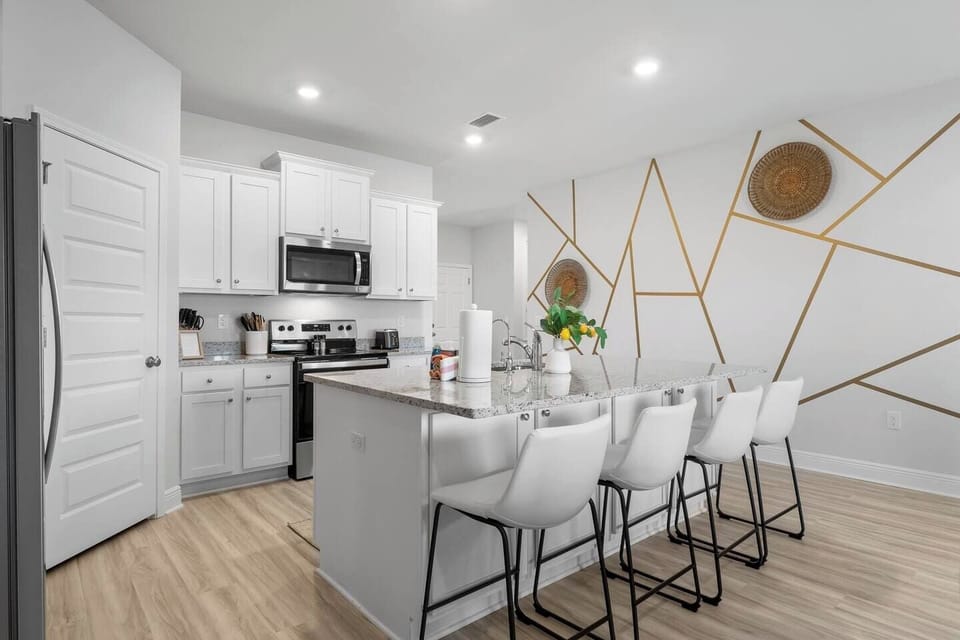 Modern full kitchen with a breakfast bar, 4 bar stools, and top-of-the-line appliances.