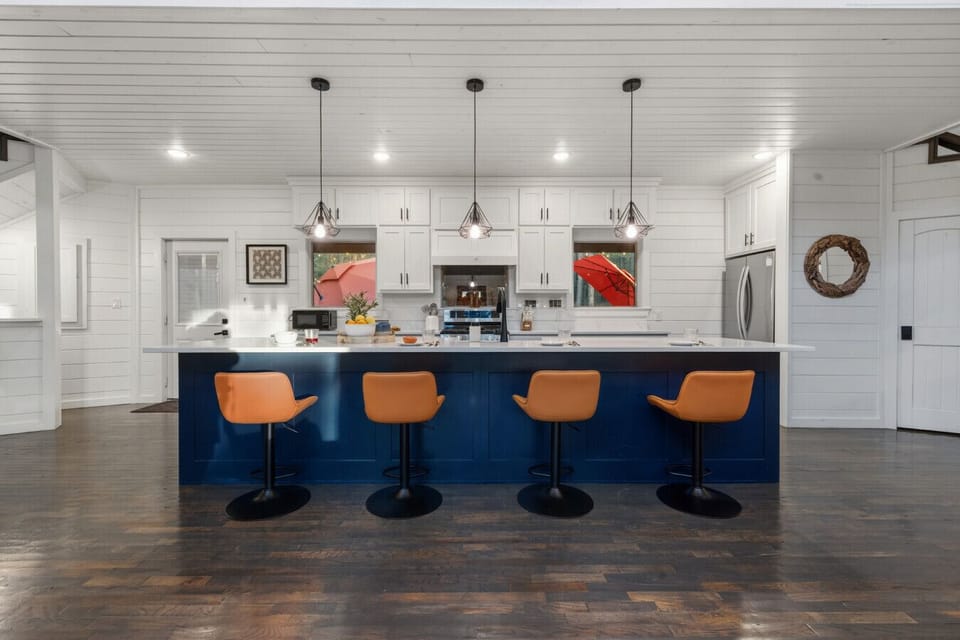 Kitchen island with navy-blue base and 4 designer bar stools — a social gathering hub at the heart of this luxury Broken Bow cabin.