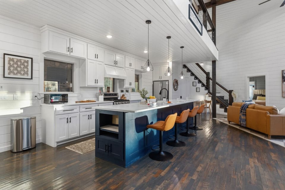 Gourmet kitchen with oversized island, 4 bar stools, custom white cabinetry, pendant lighting & full suite of stainless appliances — everything you need for a chef-worthy stay.