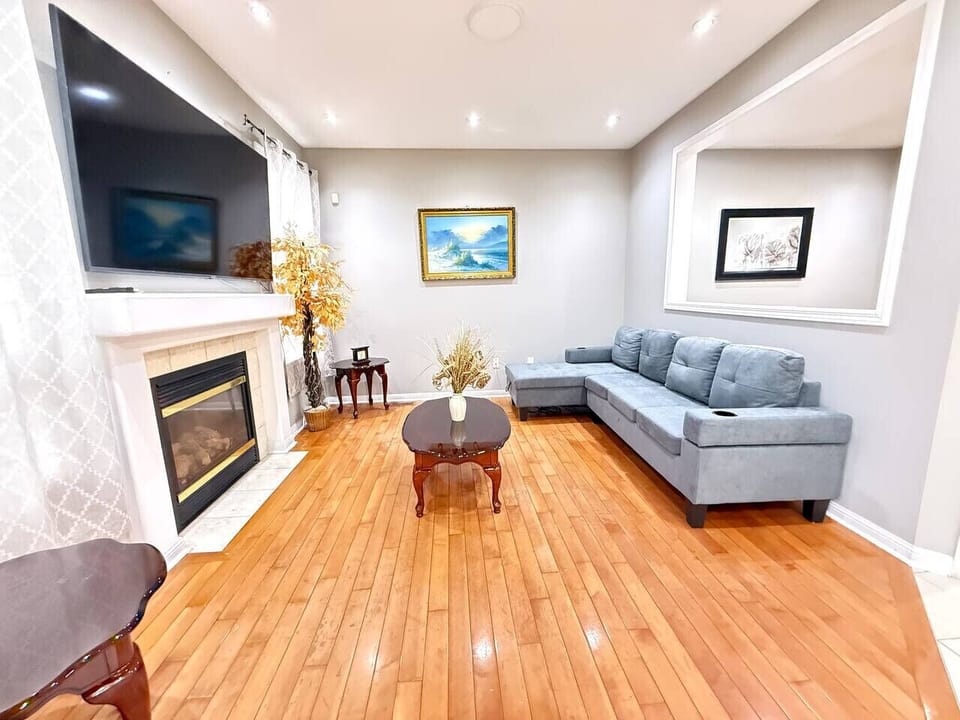 Relax and recharge in this bright, spacious living room made for comfort and connection. Stretch out on the plush sectional, enjoy movie nights on the large flat-screen TV, or cozy up by the fireplace after a long day. Sunlit hardwood floors, modern reces