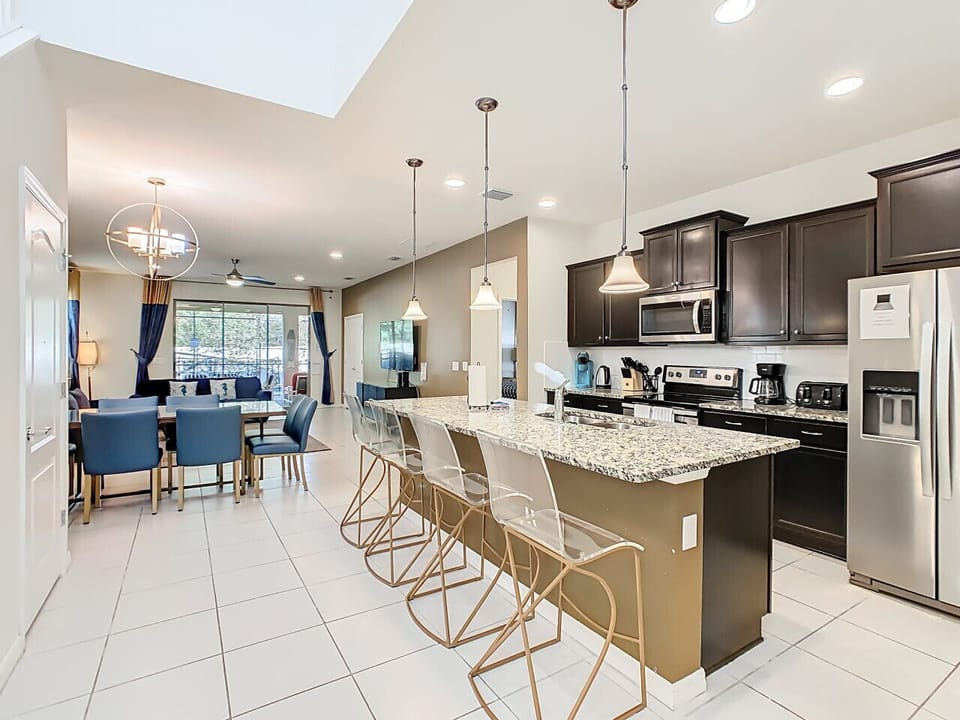 Open kitchen with bar seating, stainless steel appliances, and dining area