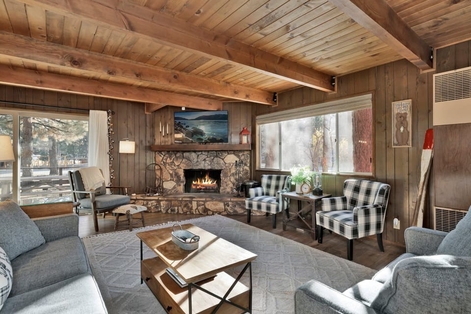 Cozy mountain living room with a stone fireplace, comfy seating, and smart TV—perfect for relaxing evenings, movie nights, and warm cabin vibes after outdoor adventures.