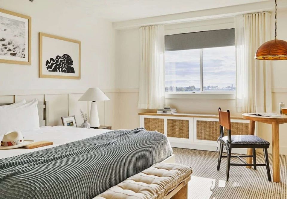 King bed room with soft bedding, desk, and natural light