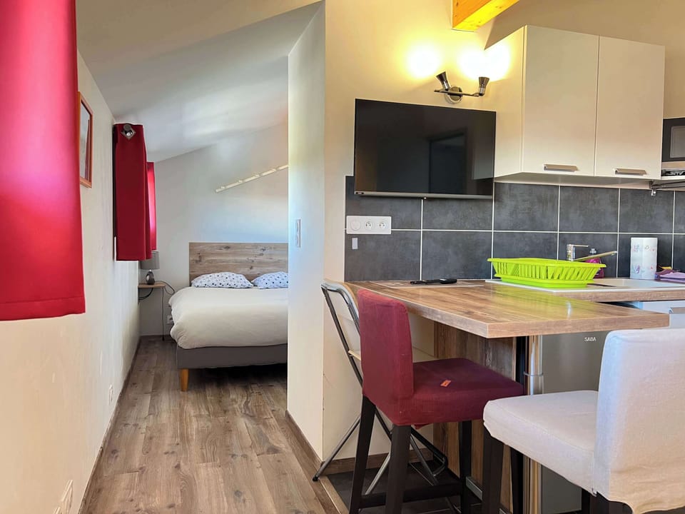 Perspective cuisine vers la chambre avec rideau rouge — distribution ouverte du T2 Le Bonnafé proche canal du Midi Toulouse