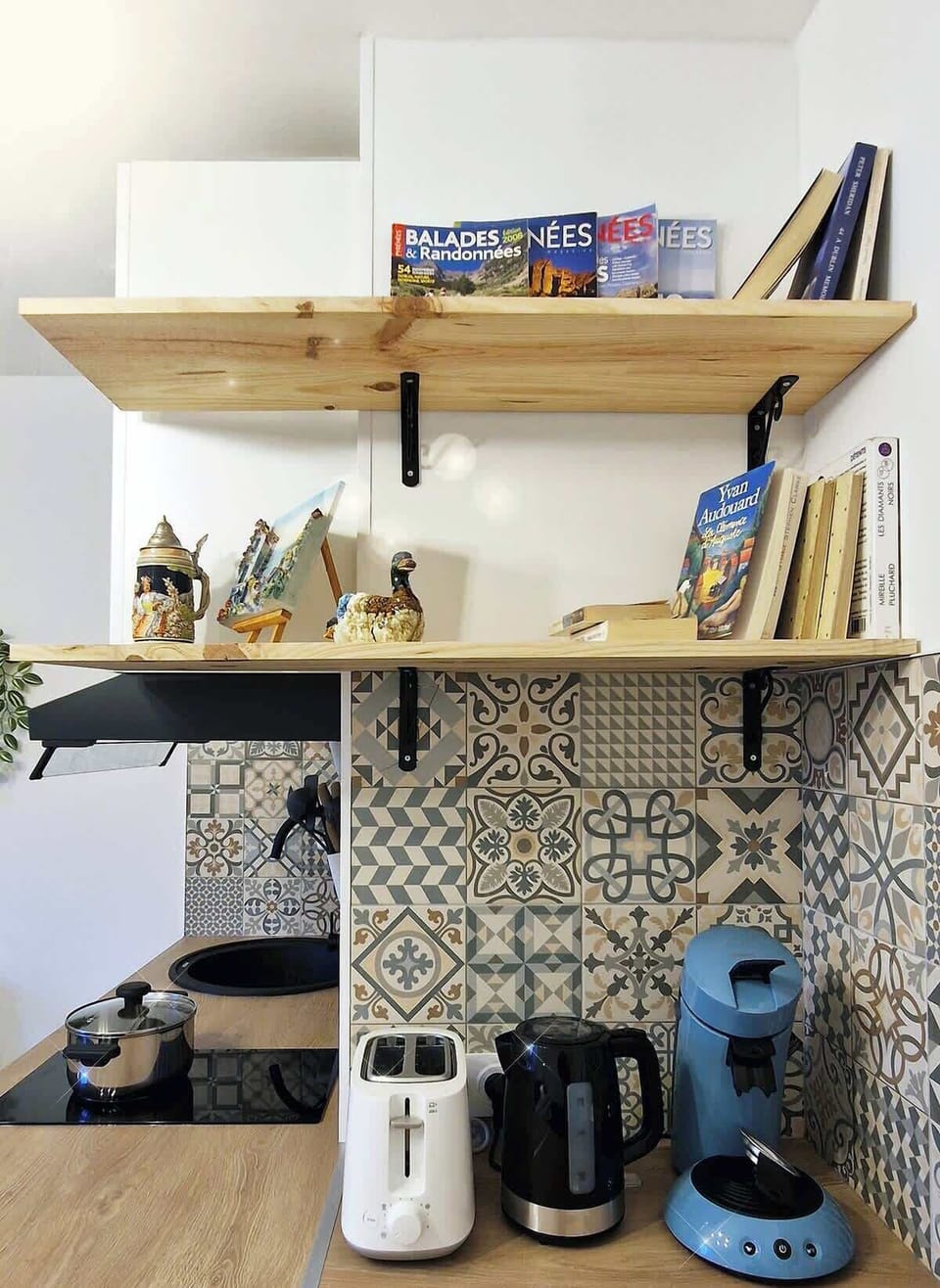 Étagères en bois avec guides touristiques, bouilloire et machine à café — coin petit-déjeuner du Chérubin